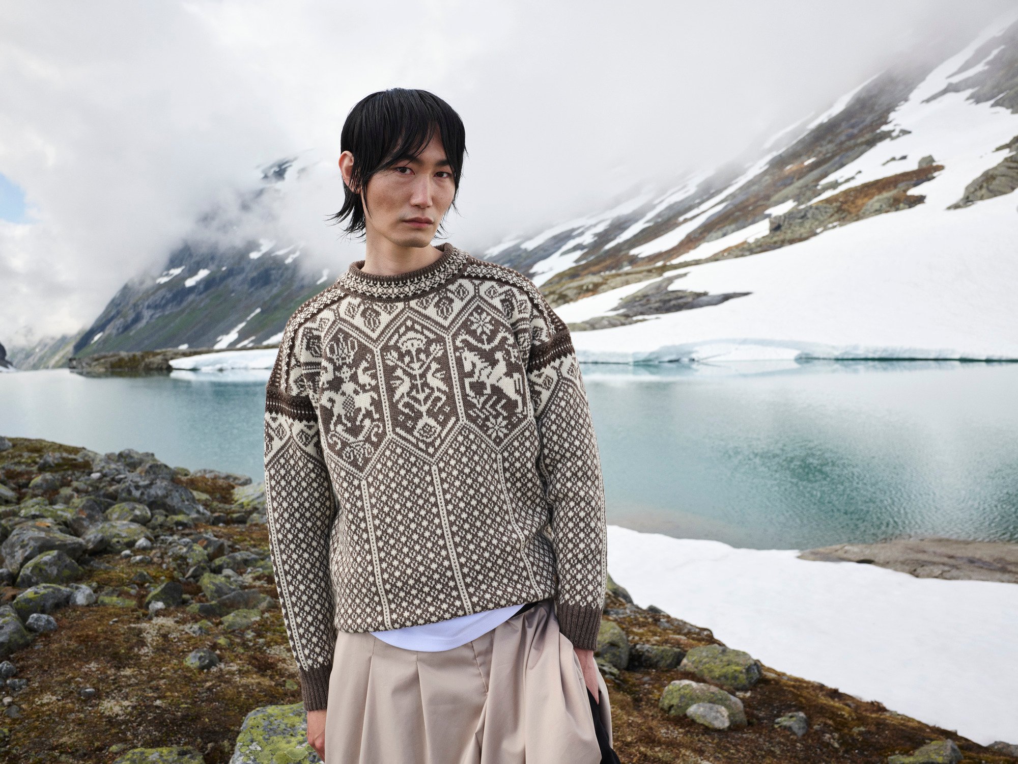 Model standing by glacier wearing wool jumper