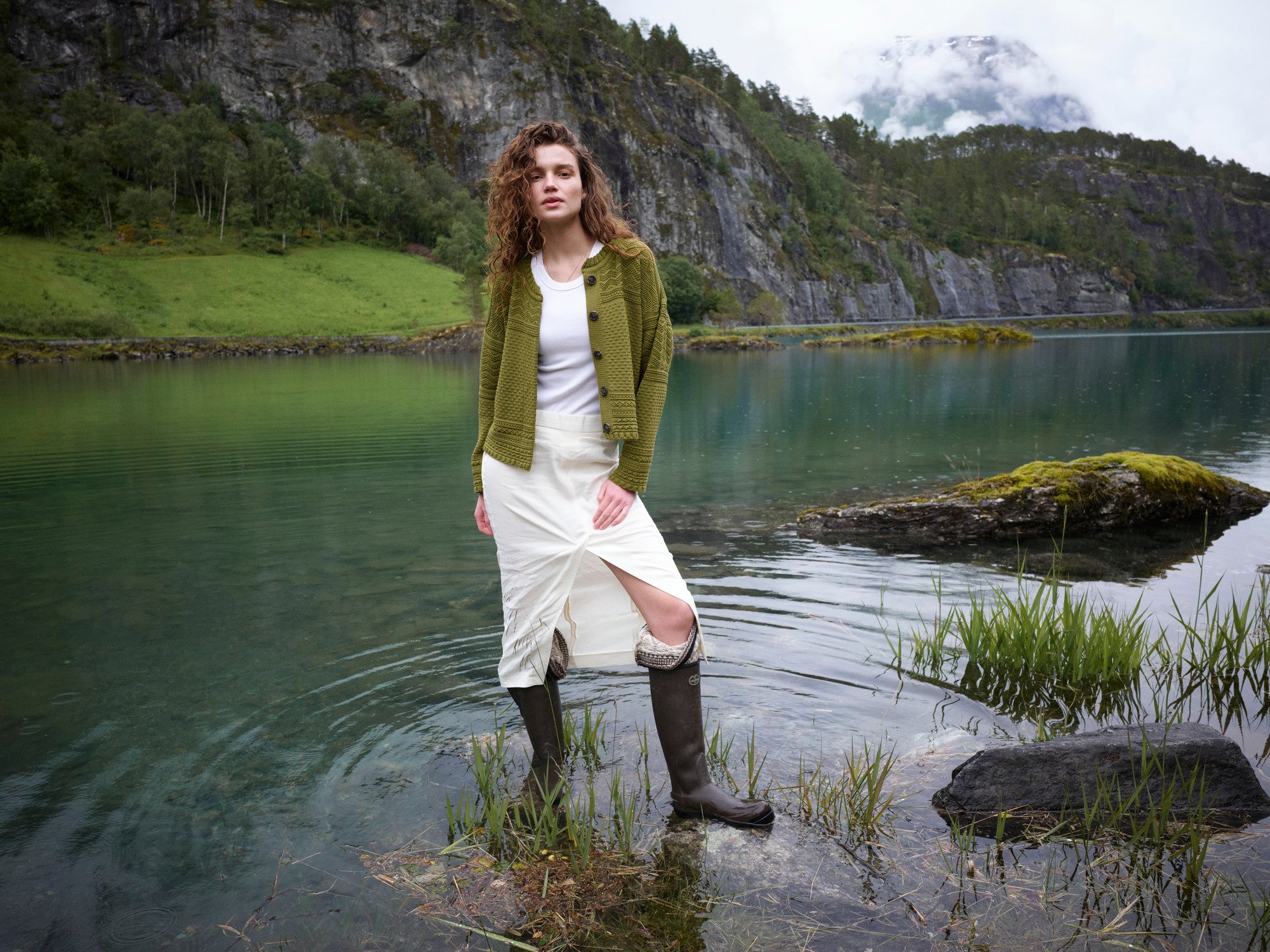 Female model standing in a Norwegian lake wearing a wool sweater