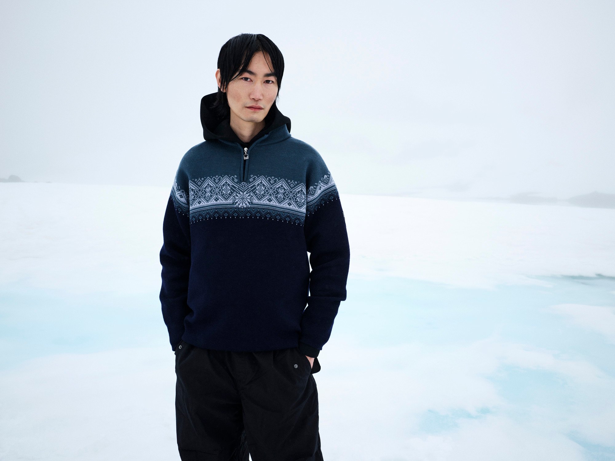 Male model wearing wool jumper standing in a snowy background