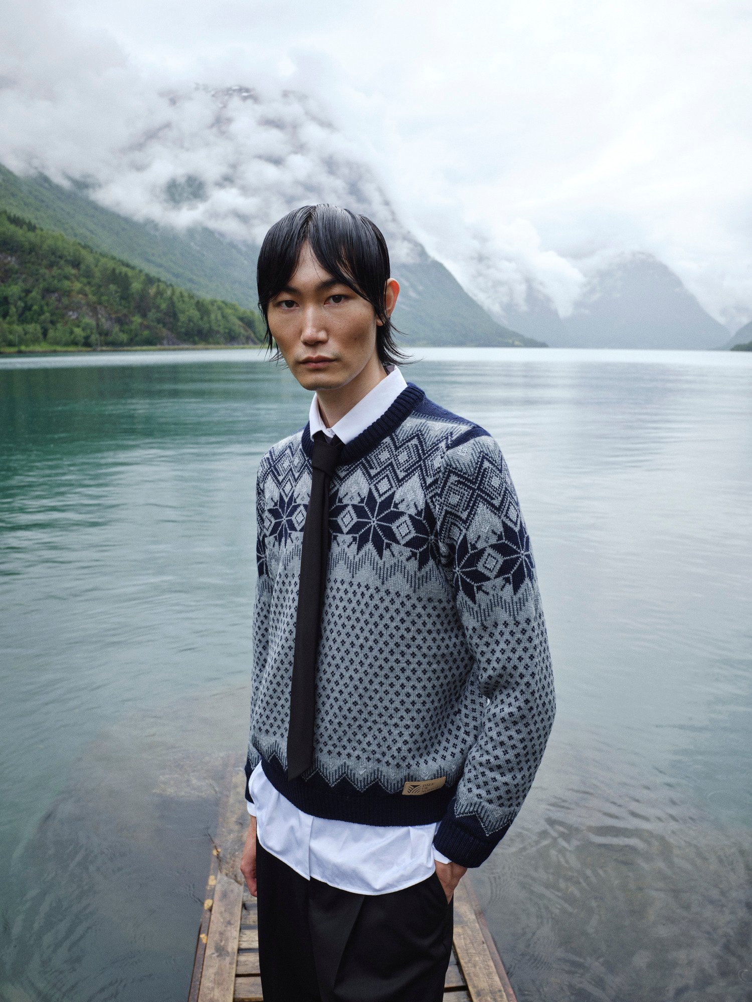 Female model wearing wool sweater standing by a Norwegian lake